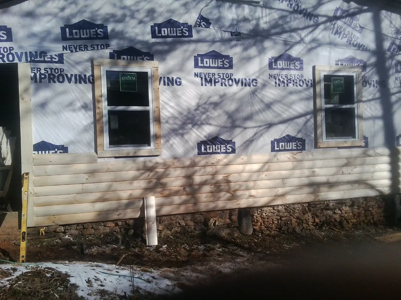 House wrap and new log siding going up on an exterior wall in Wauchula